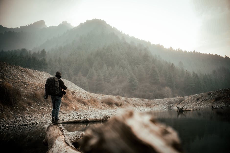 A lone backpacker walking along a serene mountain path with dense forests