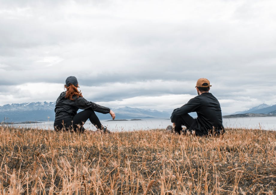 Couple sitting on grass, admiring a lake in Ushuaia, Argentina